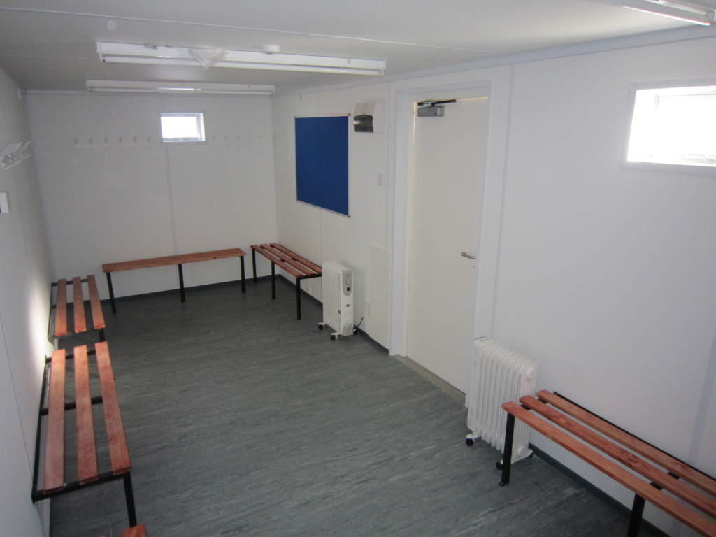 One of Flintham Cabin's new shipping container used as a changing room, with benches, heaters, and hangers