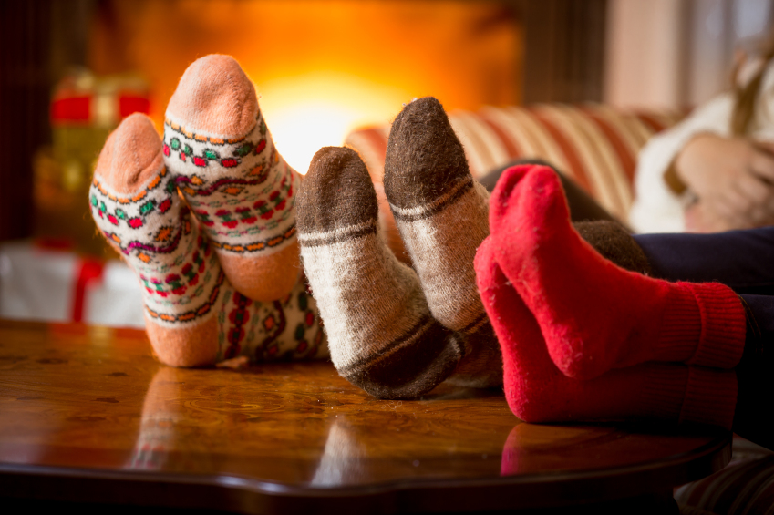 Closeup of family feet in wool socks at fireplace