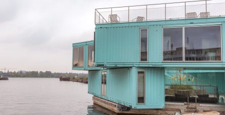 Teal blue shipping containers converted to holiday home on the edge of a lake
