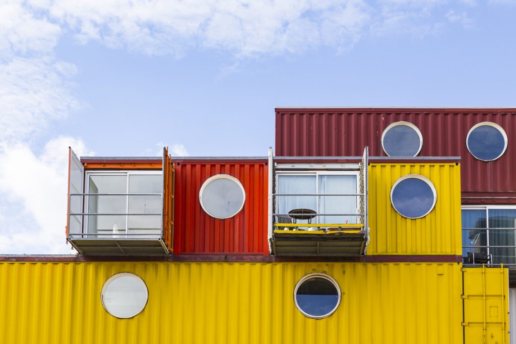 Bright red and yellow shipping containers converted into holiday homes on a sunny day with round windows